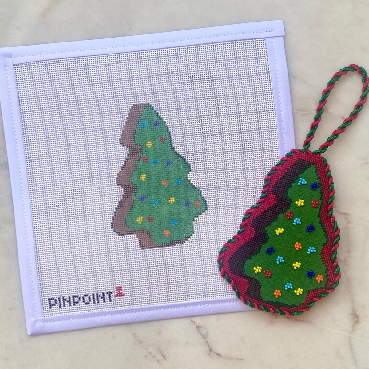 Finished beaded Cosmic Brownie Christmas tree needlepoint ornament shown with its painted canvas from @pinpointneedlepoint on Instagram